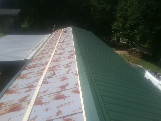Old rusted panels beside newly installed green metal roofing — Wind Damage Roof Repair by Roofing Brothers in Pinetops