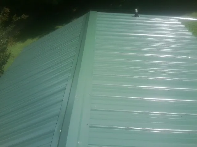 New green metal panels meeting at the ridge of a roof — Flat Roof Repair work by our crew in Pinetops