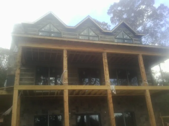 Dormers and porch framing on a large log home under construction — Roof Coating work by our crew in Pinetops