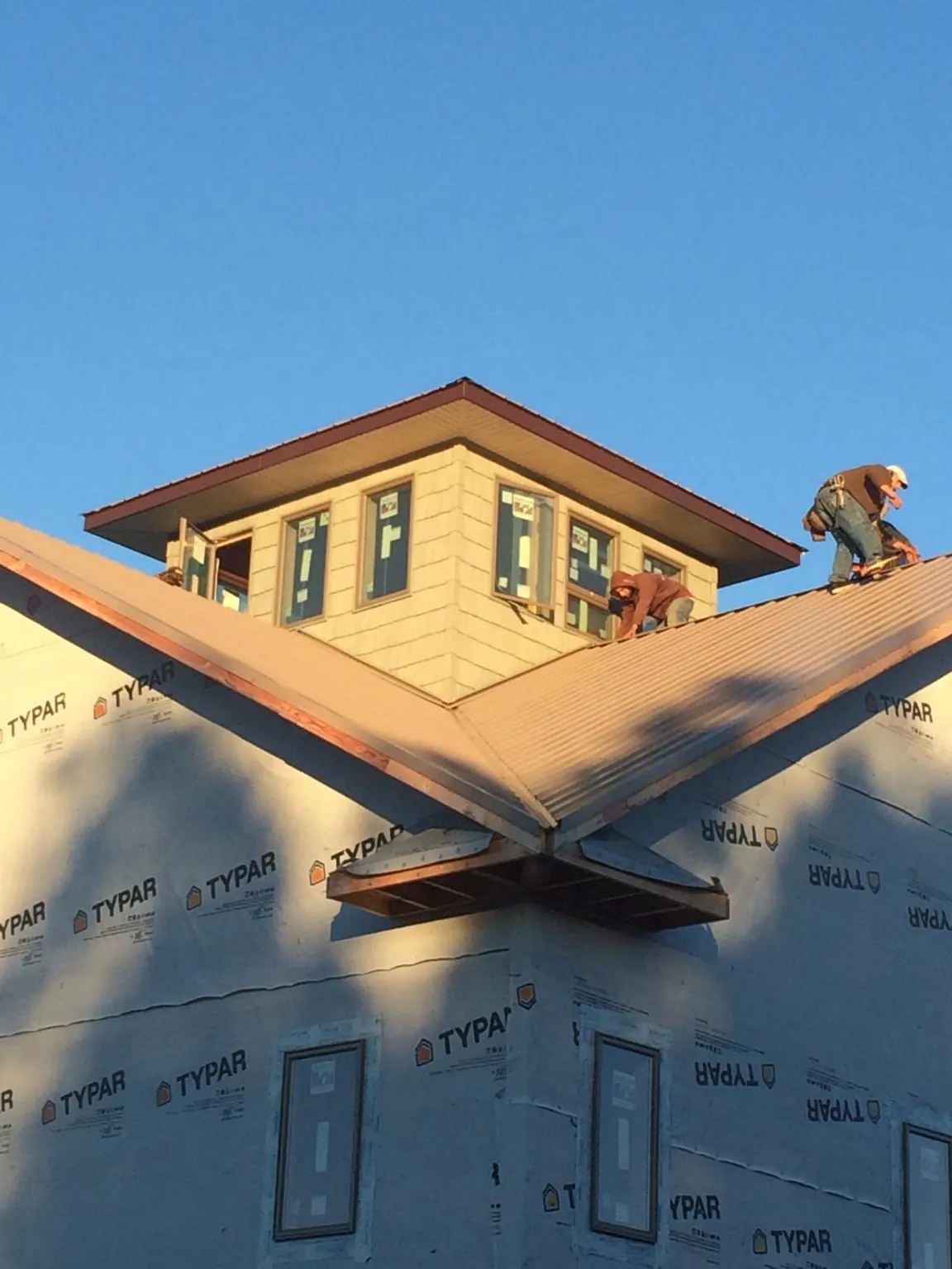 Roofers working around a rooftop cupola on a new metal roof at sunset — Roof Waterproofing in Pinetops by Roofing Brothers
